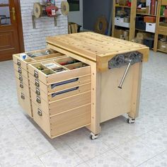 a wooden workbench with drawers and tools in the drawer compartment on wheels is shown