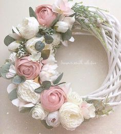 a white wicker wreath with pink and white flowers