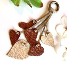 two hearts shaped keychains are hanging from a pair of leather heart - shaped keys