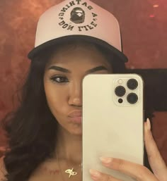 a woman taking a selfie in front of her cell phone wearing a hat and cap