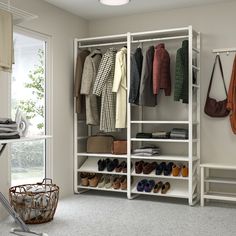 an organized closet with shoes, coats and handbags on the shelves in front of a window