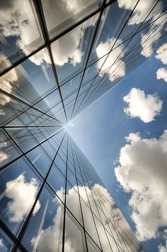 looking up at the sky and clouds in an office building's glass facades