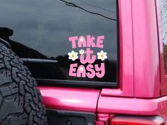 a sticker that says take it easy on the back of a pink truck with flowers