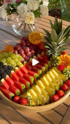 a bowl filled with lots of different types of fruit on top of a wooden table