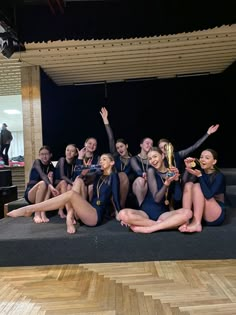 a group of young women sitting next to each other on top of a wooden floor