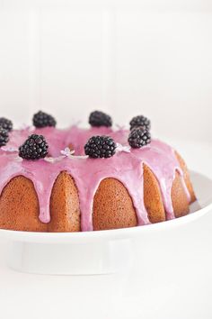 a bundt cake with pink icing and blackberries on top