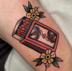 a tattoo on the arm of a man with flowers and a bird in a box