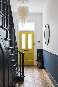 a yellow door is on the side of a staircase next to a black banister