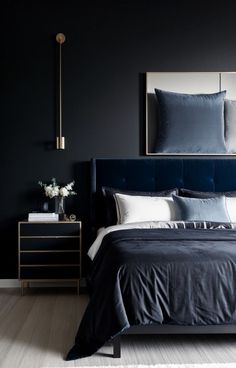 a bedroom with black walls, white and blue bedding and two lamps on either side of the bed