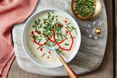 a bowl of soup with green beans and red peppers on a plate next to an ornament