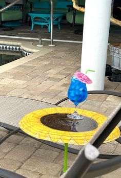 a blue and yellow drink sitting on top of a table next to a swimming pool