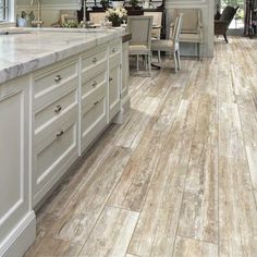 a large kitchen with white cabinets and marble counter tops, along with hardwood flooring