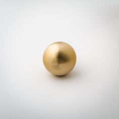 a shiny gold ball on a white surface