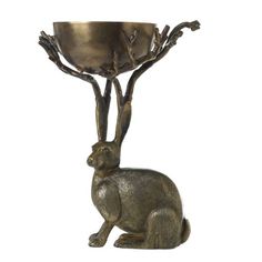 a metal cat sitting next to a bowl on top of a tree branch with branches