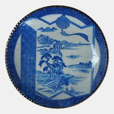 a blue and white plate with an image of a bird flying over the ocean on it