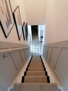 the stairs are lined with carpet and framed pictures on the wall above them, along with black and white flooring