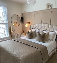 a large bed sitting next to a window in a bedroom with white walls and furniture