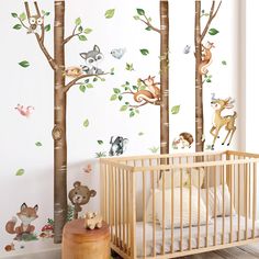 a baby's room with trees and animals on the wall, including a crib