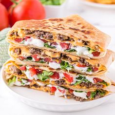 two quesadillas stacked on top of each other with tomatoes and lettuce