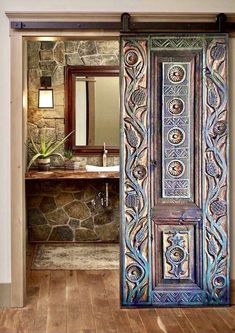 an open door leading to a bathroom with stone walls and wood floors, along with a sink