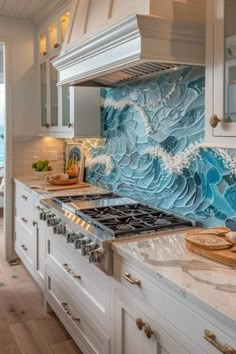 a kitchen with white cabinets and blue waves on the backs splashing down the wall