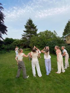 a group of people standing on top of a lush green field next to each other