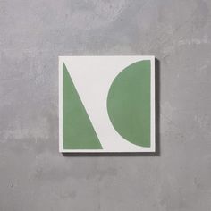 a white and green square with a leaf on the side, against a gray wall