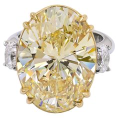 a fancy yellow diamond ring with three diamonds on the sides and an oval center stone