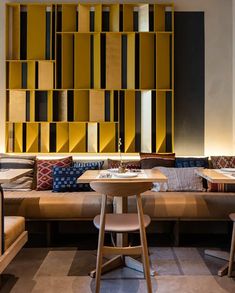 a room with couches, tables and chairs in front of a wall made out of bookshelves