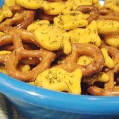 a blue bowl filled with lots of pretzels covered in mustard and seasoning