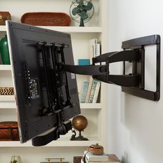 a flat screen tv mounted to the side of a wall next to a book shelf