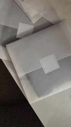 three envelopes sitting on top of each other in white and grey paper with squares