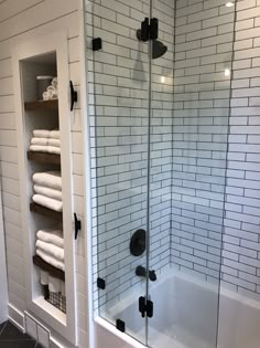 a bathroom with a glass shower door and white towels on the shelves in front of it