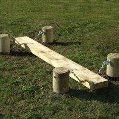 a wooden bench sitting on top of a lush green field next to a cement bucket