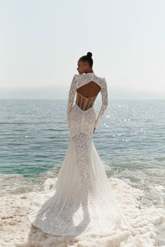 a woman standing on top of a beach next to the ocean wearing a wedding dress