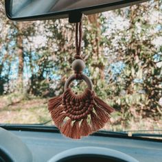 a car dashboard with a tassel hanging from it's side mirror and trees in the background