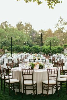 an outdoor wedding reception with white linens and wooden chairs