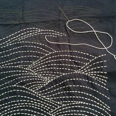 a piece of cloth with white thread on it and an image of waves in the background