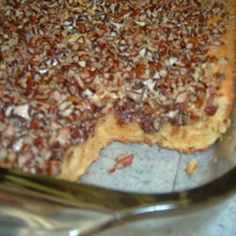 a close up of a pie in a pan with pecans on the top and one slice missing