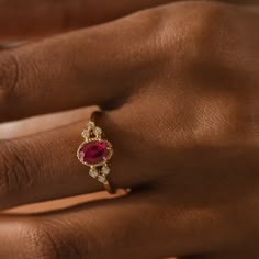 a woman's hand with a ring on it and a red stone in the middle