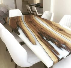 a dining room table with white chairs and a large wooden slab on it's center