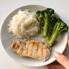 a white plate topped with rice and broccoli next to meat on top of it