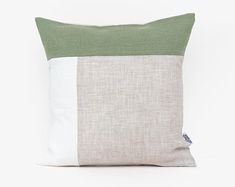 a green and white pillow on a white background