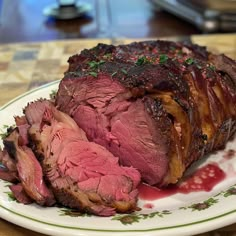 a piece of roast beef on a plate with red sauce and garnishes