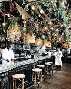 a man standing at the bar in front of some hanging plants and baskets on the wall