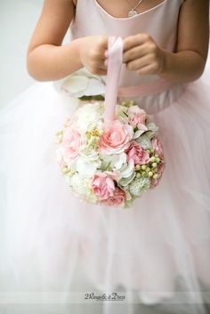 a woman in a pink dress is holding a bouquet with white and pink flowers on it