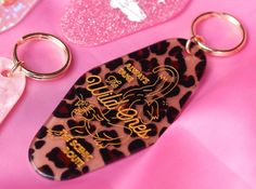 a leopard print keychain sitting on top of a pink table with other items