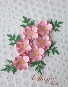 some pink flowers are on top of white polka dot paper with green leaves in the middle