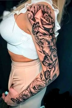 a woman's arm with roses and butterflies tattooed on the side of her body