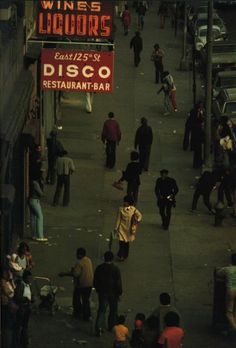 an overhead view of people walking down the sidewalk in front of liquor stores and restaurants